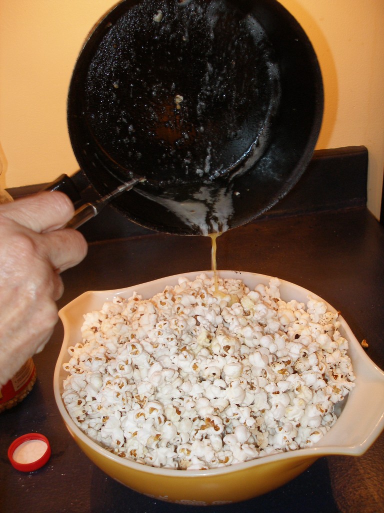 Pour the butter that you've melted in your battered, abused vintage pan onto the warm popcorn.